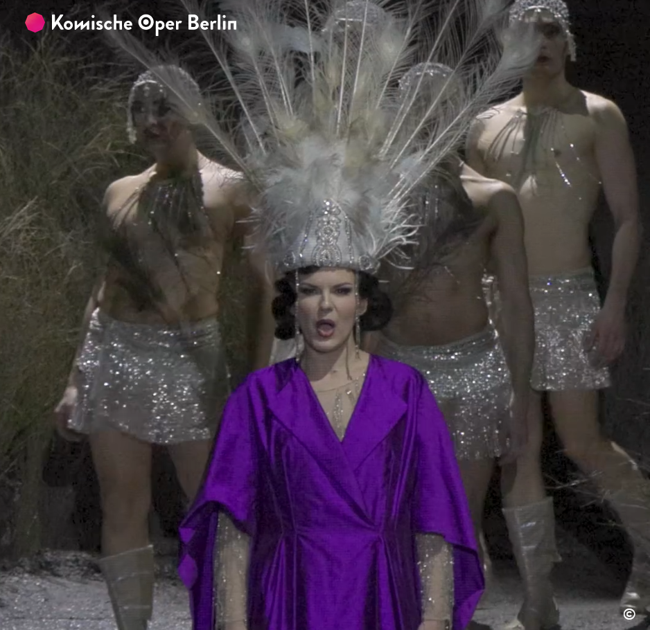 Kseniia Proschina steht mit violettem Kleid und grossem Federputz vor den vier Tänzern